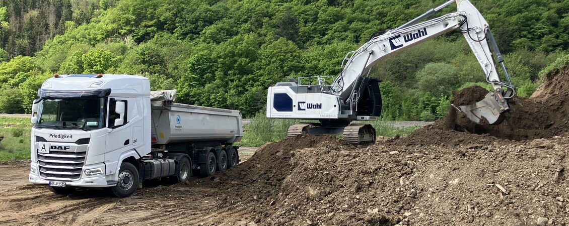 Ein LKW wird von einem Bagger beladen
